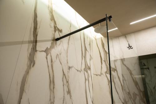 a white marble wall in a bathroom with a shower at Ku Private Milano in Pero