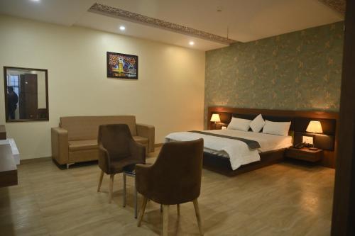 a bedroom with a bed and a couch and chairs at Hotel Vinayak International in Muzaffarpur