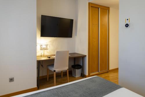 a bedroom with a desk and a television on the wall at Alda Ruta Castilla in Palencia