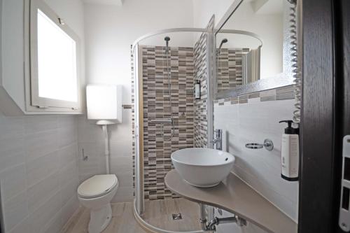 a white bathroom with a sink and a toilet at Bikini Tropicana Family Hotel in Lido di Savio