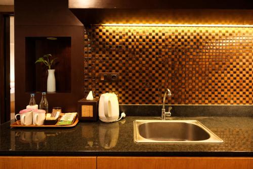 a kitchen counter with a sink and a mirror at Metland Seva Seminyak - Formerly Horison Ultima Seminyak in Seminyak