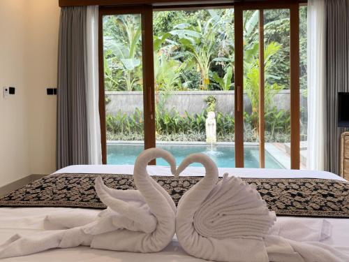 two white swans making a heart on a bed at Pondok Lekad D'ubud in Ubud