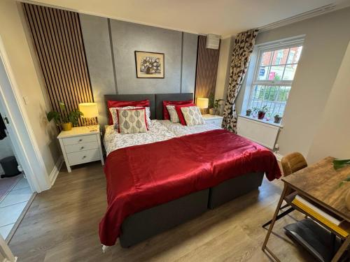 a bedroom with a large bed with a red blanket at Chrysanthemum Drive stays in Shinfield