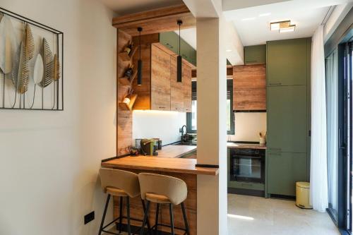 a kitchen with green cabinets and a counter with stools at Casa Oliva Tivat in Tivat