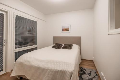 a white bedroom with a bed and a window at Lumi Apartments in Rovaniemi