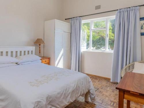 a bedroom with a white bed and a window at Kusweg Oos 1 in Struisbaai