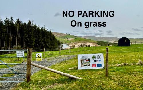 a sign that says no parking on grass next to a fence at Forester's Retreat Glamping - Dinas View - Dogs over the age of 2 with vaccination accepted RALI CEREDIGION EVENT 4TH-6TH SEP 2026 in Aberystwyth