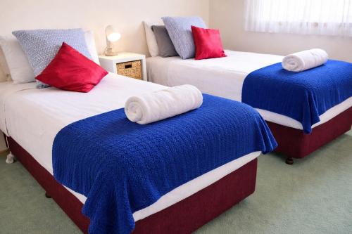 two beds with blue and red pillows in a room at Kennington Units Family in Kennington