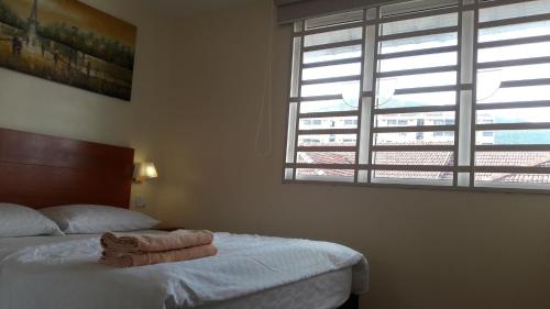 a bedroom with a bed and a large window at Penang Hill Lodge in Ayer Itam