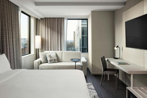 a hotel room with a bed and a chair and a desk at AC Hotel by Marriott Ann Arbor Downtown in Ann Arbor
