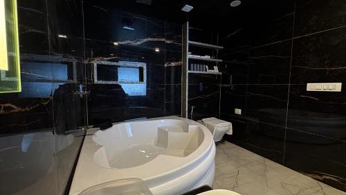 a bathroom with a bath tub and a toilet at Emroz Kings Resort in Batakūt