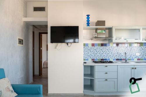 a kitchen with white cabinets and a tv on a wall at Hotiday Gallipoli Lungomare in Gallipoli