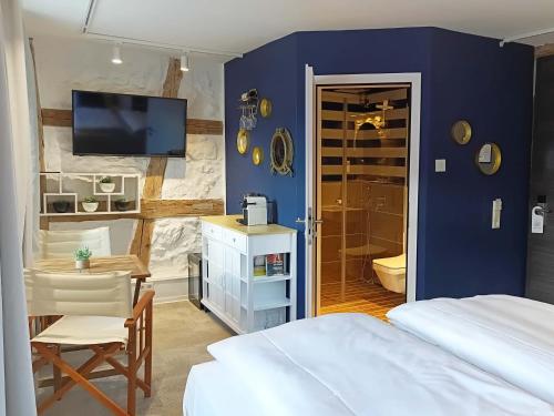a bedroom with a blue wall with a bed and a bathroom at NOX HOTEL - Digital-Check-In - No Reception - nahe Bretten & Karlsruhe - 2 Nautic in Wössingen