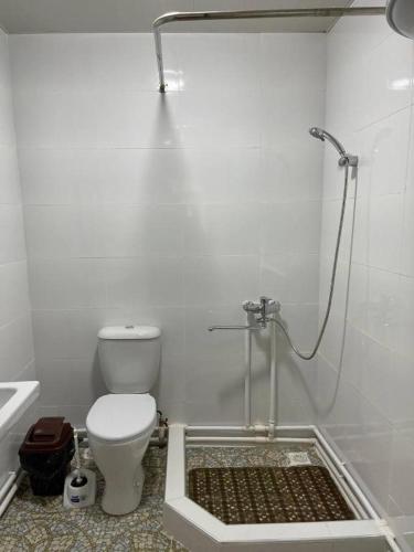 a white bathroom with a toilet and a shower at Shirin Ethno House Yurt Camp in Shirin