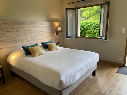 a bedroom with a large white bed with a window at Hôtel Le Mas del Pechs - Chambres avec terrasse in Sarlat-la-Canéda