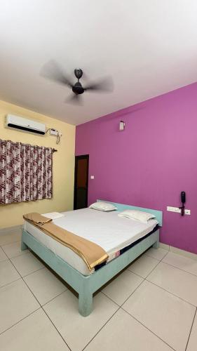 a bed in a room with a purple wall at Gravity Groups VHR Residency - near santho lawns in Pondicherry