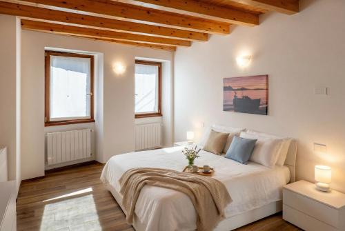 a bedroom with a large white bed and two windows at Ca da Smarè - Where Time stands Still in Someraro