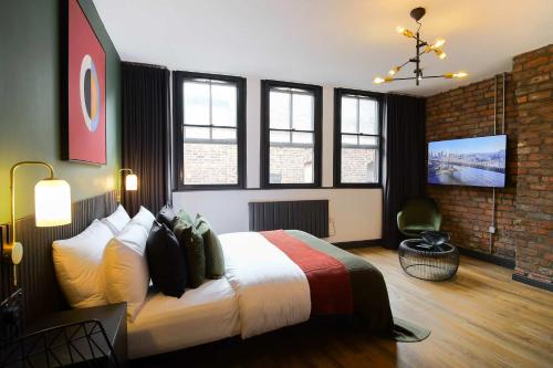 a bedroom with a large bed and a tv at Stylish Northern Quarter Studio, Ideal for Leisure & Work Stays in Manchester