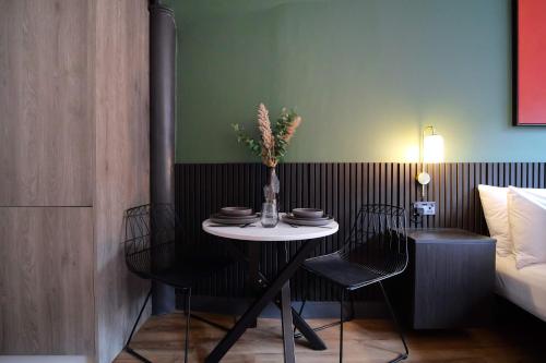 a table with chairs and a vase of flowers on it at Stylish Northern Quarter Studio, Ideal for Leisure & Work Stays in Manchester