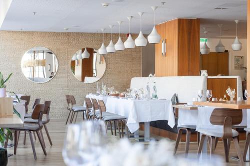 a restaurant with white tables and chairs and mirrors at Renaissance Aix-en-Provence Hotel in Aix-en-Provence