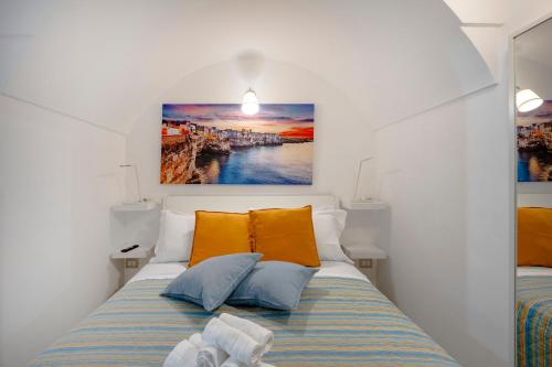 a bedroom with a bed with orange and blue pillows at Case D'Amare - Tritone 30 in Polignano a Mare