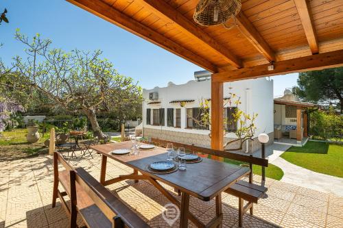 a patio with a wooden table and chairs at Estay - Casa Madili - Garden - BBQ - WiFi in Sarroch