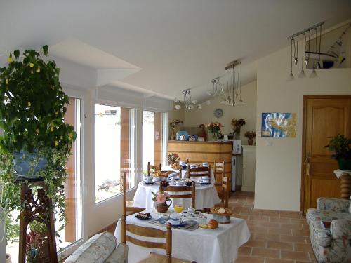 a living room with tables and chairs and a kitchen at La Grande Mare in Saint-Benoît-des-Ondes