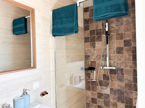 a bathroom with a shower with blue towels and a sink at Strandhuis Scheveningen - Studio Apartments in Scheveningen