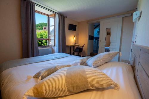 a bedroom with a large bed with a window at Hôtel-Restaurant Au Moulin d'Alexandre in Sainte-Eulalie-dʼOlt