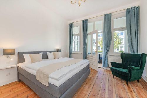 a bedroom with a large bed and a green chair at Villa Tanneck App 1 in Ahlbeck