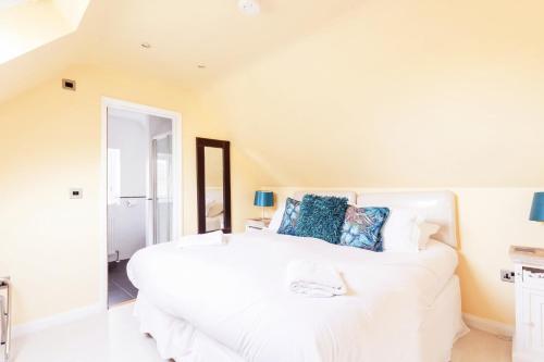 a bedroom with a large white bed with blue pillows at Hunter Heights Loft – Near Ventnor, Isle of Wight in Wroxall