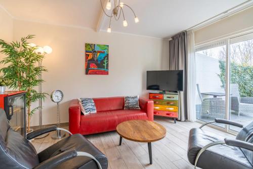 a living room with a red couch and a tv at Californiëweg 9A in De Koog