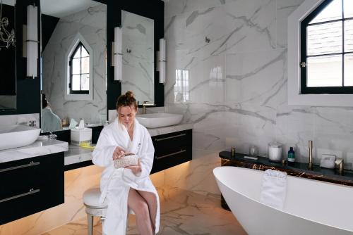 a woman sitting in a bath tub in a bathroom at Inn at Taughannock Falls in Ithaca