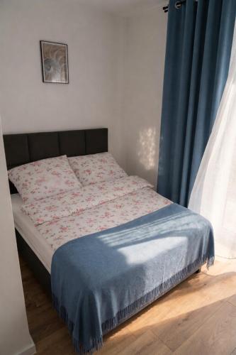 a bed in a bedroom with a blue curtain at Apartamenty Raszyn in Raszyn