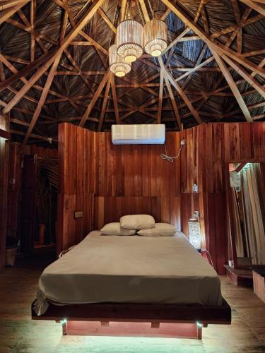 a large bed in a room with wooden walls at Bonomali Mangrove Resort in Dhāngmāri Forest Office
