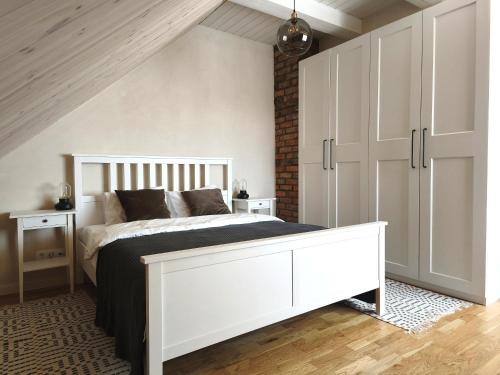 a bedroom with a white bed and a white cabinet at Loft Apartment Self Check-in in Mažeikiai