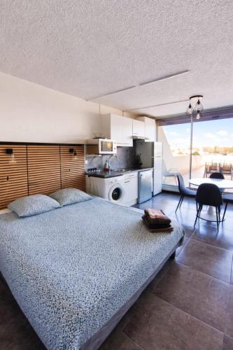 a bedroom with a large bed and a kitchen at Naturiste Cap d'Agde Héliopolis K 106 in Cap d'Agde