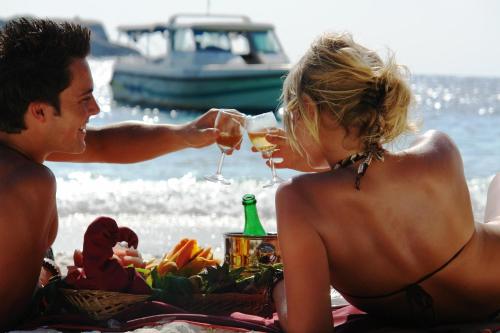 a man and a woman sitting on the beach with wine glasses at BuBu Villa in Perhentian Islands