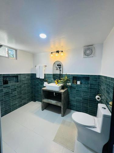 a bathroom with a sink and a toilet and green tiles at Bintana sa Paraiso Binunsaran in Mambajao