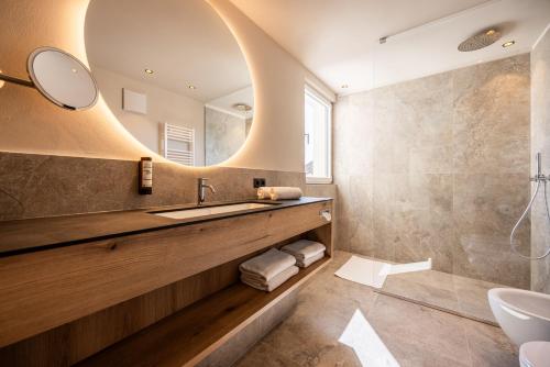 ein Badezimmer mit Waschbecken und Spiegel in der Unterkunft EGGER Apartments & Suites in Villanders