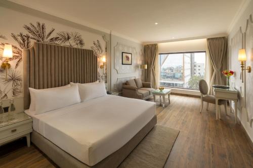 a bedroom with a large white bed and a living room at Clarks Inn Bokaro in Bokāro