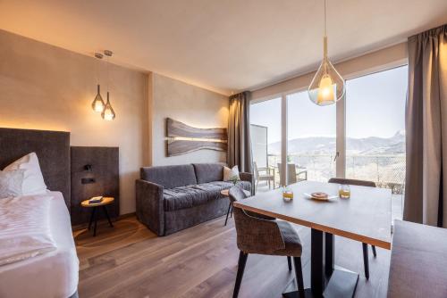 ein Hotelzimmer mit einem Bett, einem Tisch und einer Couch in der Unterkunft EGGER Apartments & Suites in Villanders