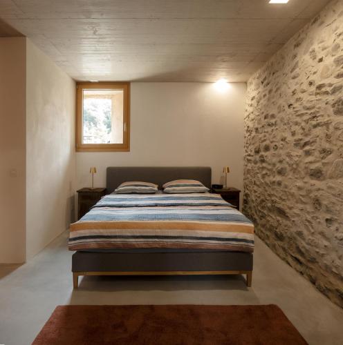 a bedroom with a bed and a stone wall at Charming Rustico Losone near Locarno in Losone