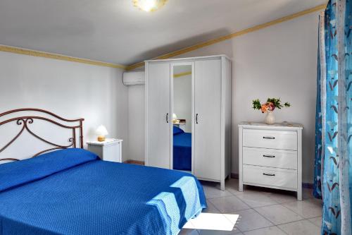 a bedroom with a blue bed and a mirror at GOCCE VILLAS - Il Frantoio in Massa Lubrense