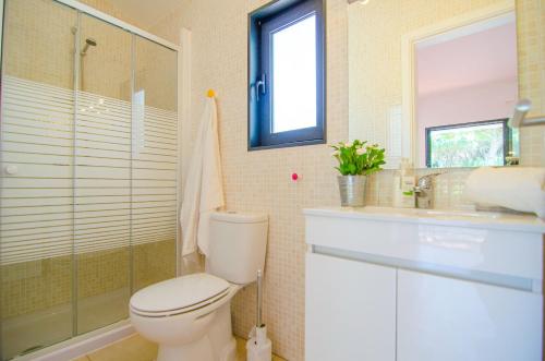 a bathroom with a toilet and a shower and a sink at Villa Beira Golf by Algarve Holidays in Quarteira