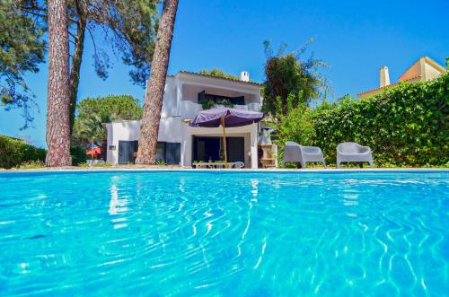 a villa with a swimming pool in front of a house at Villa Beira Golf by Algarve Holidays in Quarteira