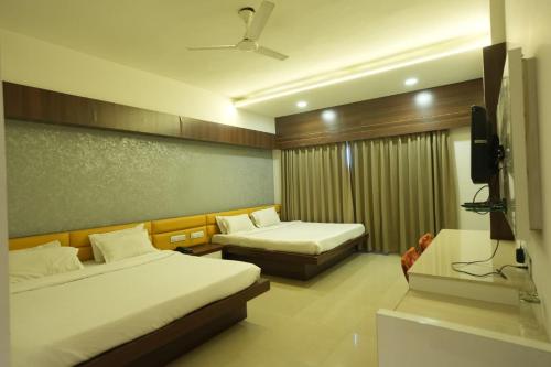 a hotel room with two beds and a flat screen tv at Hotel Waterlily in Indore