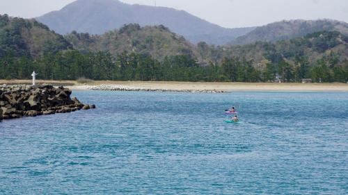 a person standing on a paddle board in the water at Base House Kinosaki お子様無料でサウナもアクティビティも楽しめる城崎温泉一棟貸し宿 One Group a Day Private Villa with free shuttle service, sauna and outdoor activities in Toyooka