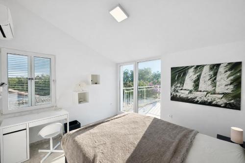 a white bedroom with a bed and a desk and window at Villa GIUSEPPE in Potocnica
