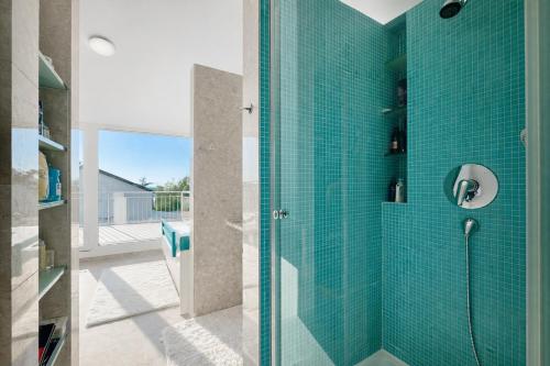 a bathroom with a glass shower with blue tiles at Villa GIUSEPPE in Potocnica